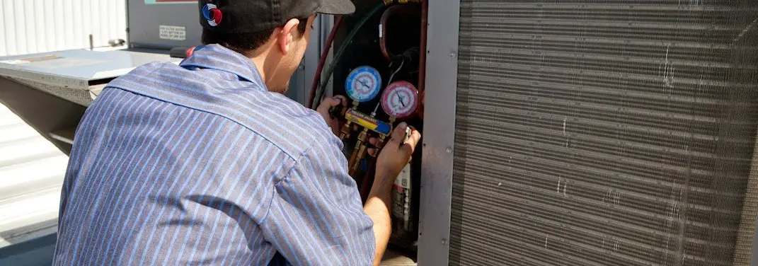 HVAC technician servicing a condenser unit in Gloucester City